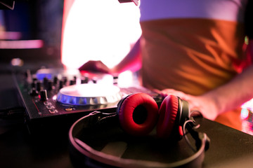 DJ Spinning, Mixing, and Scratching in a Night Club, Hands of dj tweak various track controls on dj