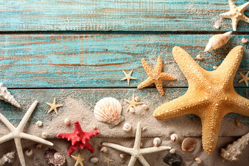 Seashell, starfish and beach sand on blue wooden background. Summer holiday concept. Top view.