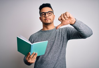 Young handsome smart student man reading book over isolated white background with angry face, negative sign showing dislike with thumbs down, rejection concept