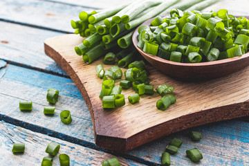 Fresh green onion chopped and lies on a bowl on a chopping board on a background of blue boards.