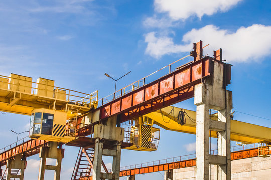 Industrial Zone, Enterprise, Construction Site With A Bridge Crane On A Background Of Blue Sky With Clouds