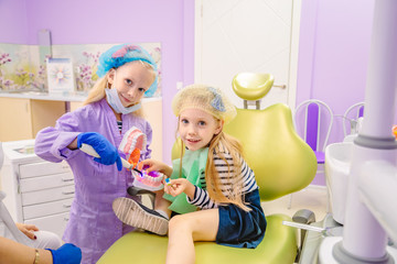 Dentist teaches children how to treat teeth.