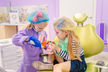 Dentist teaches children how to treat teeth.