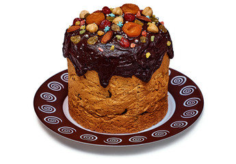 Sweet Easter cake poured with chocolate and decorated with dried fruits from dried apricots, candied fruits, cherries, raisins and also hazelnuts, almonds and seeds isolated on a white background