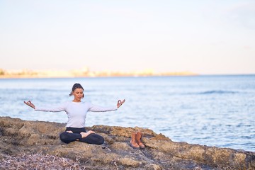 Fototapeta na wymiar Young beautiful sportwoman practicing yoga. Coach teaching lotus pose at the beach