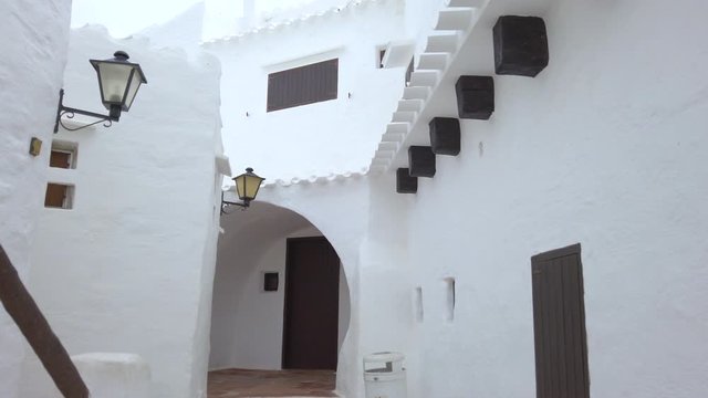 Walking through old traditional menorcan fishing village Binibeca Vell. Narrow streets and charming white houses natural maze. Balearic Island, Menorca coast, Spain.