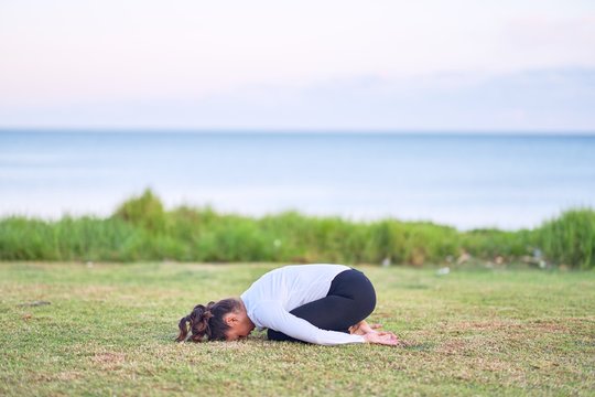 Young beautiful sportwoman practicing yoga. Coach teaching postures at park