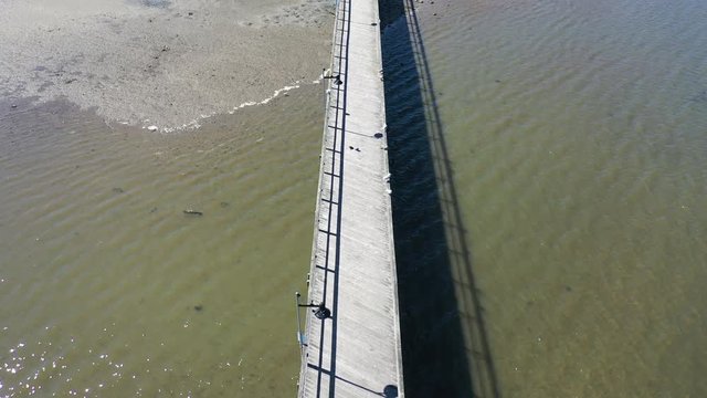 A top down shot, taken directly over a wooden pier in Little Neck Bay, Queens, NY. The camera moves forward while slowly tilting down. It was shot at low tide on a bright & sunny day.