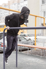 A lonely man in a respiratory mask sits on a ground on a deserted city during a coronavirus epidemic in beautiful spring time. Russia, Samara, april. Selective and soft focus.