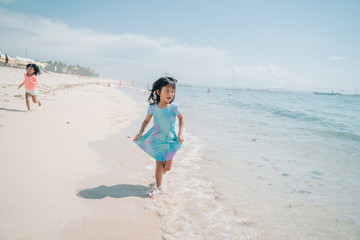 asian little girls run and laugh while enjoying the beautiful beach