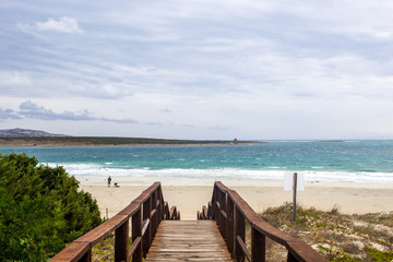 Fototapeta premium Amazing view onto the Mediterranean Sea and sky with clouds. A stair heads down to access La pelosa Beach on Sardinia Island in Italia.