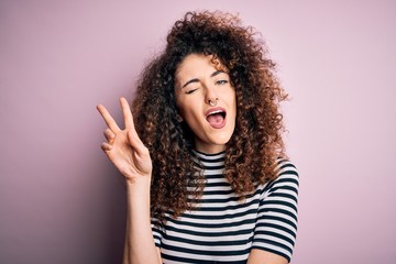 Young beautiful woman with curly hair and piercing wearing casual striped t-shirt smiling with...