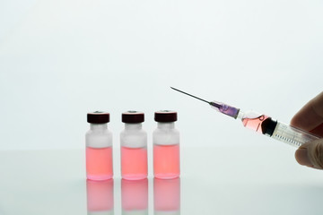 hand holding syringe and red drug in vial bottle for medical disease treatment white background