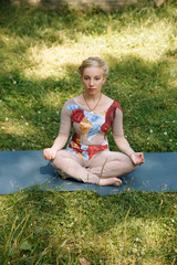 Beautiful young woman doing yoga in the summer park. Healthy lifestyle. Yoga. Lotus pose.