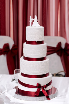 Wedding Cake White Cream Mastic Four Floors With Red Ribbons And Bow With Newlyweds From Above On A White Background