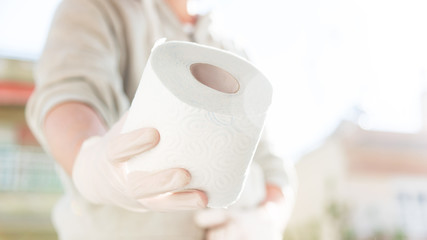 Caucasian male hand in surgical glove holding or giving a roll of toilet paper