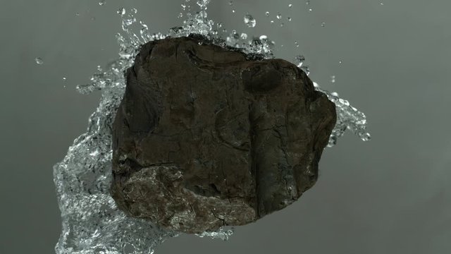 Piece of coal wit water splashing. Cosmetic concept of skin and face care. Filmed on super slow motion camera, 1000 fps.