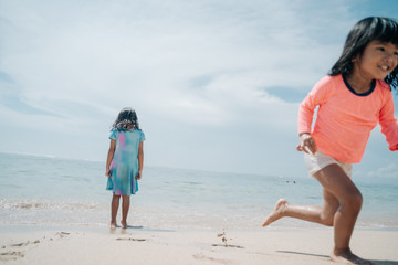 two little girls playing hide and seek, playing on the beach enjoying the pleasure of vacationing