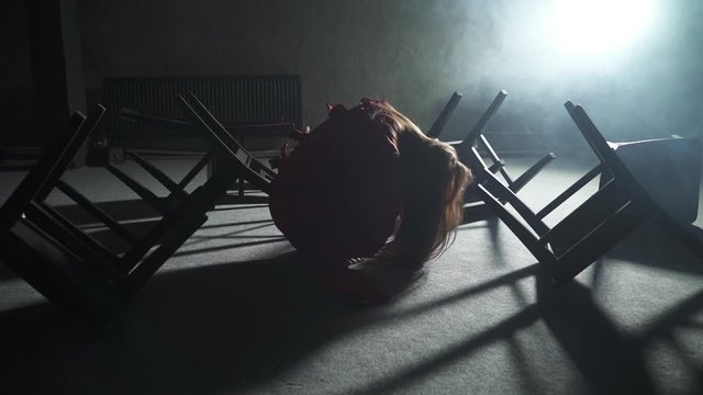 a girl in a red straitjacket in a psychiatric clinic sits on the floor among the chairs around