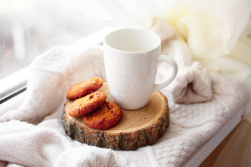 a Cup of tea with oatmeal cookies is on the window, a knitted sweater, an old Flat lay book