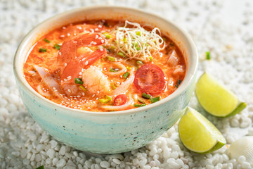 Homemade Tom Yum soup in blue bowl with lime