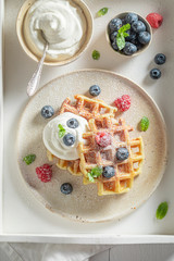Sweet and homemade waffles with whipped cream and berries