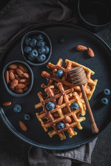 Top view of waffles with honey, almont and blueberries
