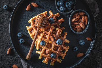 Top view of homemade waffles with blueberries, honey and almont