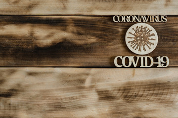Symbol, inscription carved from CORONAVIRUS plywood, COVID-19 on a brown wooden surface.