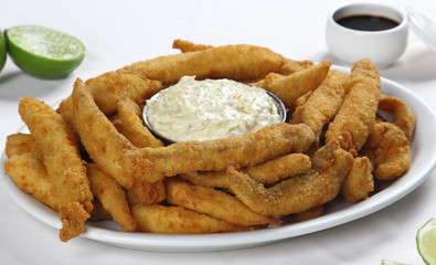 fish fingers served with mayonnaise sauce on a white plate.