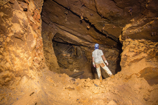 Miner explorer in abandoned bauxite ore mine tunnel board-and-pillar work cavity