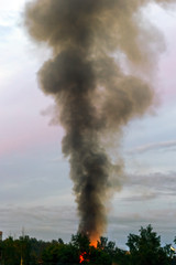 the building burns with fire and black smoke against the evening sky
