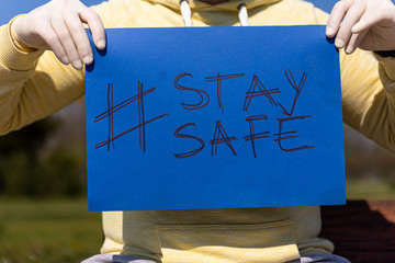 Stay safe sign on blue chroma key paper held by a man in surgical gloves