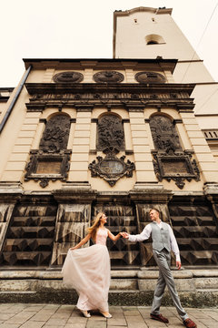 newlyweds hold hands and walk. wonderful architecture of a medie