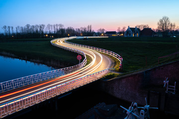 Fototapeta na wymiar Curve light trails on country road in the landscape of the province of Groningen, The Netherlands