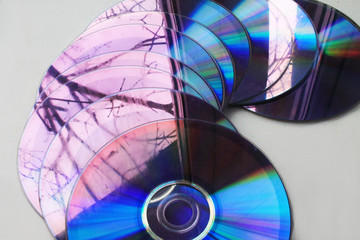 Old used computer disks on a white background with a rainbow stripe. Reflection of trees from the window.