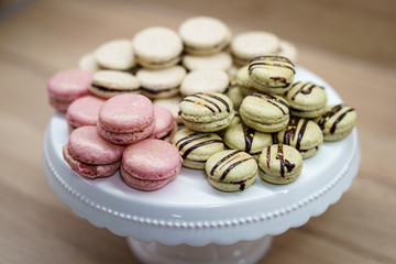 White pink and green macaroons on white plate