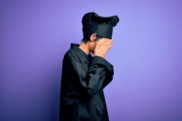 Young beautiful chinese chef woman wearing cooker uniform and hat over purple background with sad expression covering face with hands while crying. Depression concept.