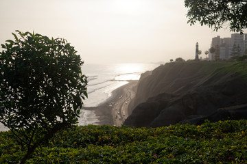 Klif na peruwiańskim wybrzeżu Pacyfiku z widoczną plażą, molem i latarnią morską.