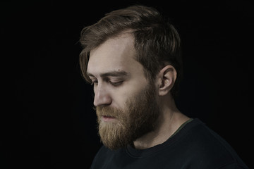 Portrait of a depressed middle aged man in a dark sweater on a dark background.