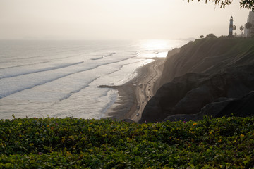 Klif na peruwiańskim wybrzeżu Pacyfiku z widoczną plażą i molem.