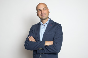 Handsome middle aged bald man is looking up over studio gray wall