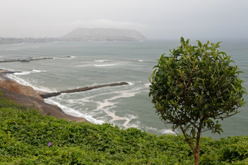Klif na peruwiańskim wybrzeżu Pacyfiku z widoczną plażą i molem.