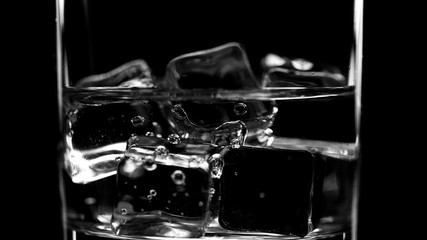 Closeup pouring clean fresh Water in a Glass with splash and bubbles, isolated on Black background. Ice, bubbles and splash. Cold tonic Mineral water. Healthy lifestyle. Living water. Drinking water.