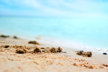 Summer background of tropical beach rest at the seaside, closeup of sand and blurred turquoise sea at sunny day