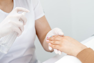 Manicurist is applying spray on client hand. Manicure disinfection with spray.