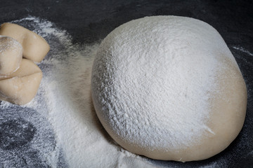 The yeast dough for bread or pizza on the surface has grown or tested on the surface with slate flour, photographed above the head with natural light (Selective Focus, Focus on top of of dough)