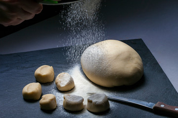 The yeast dough for bread or pizza on the surface has grown or tested on the surface with slate flour, photographed above the head with natural light (Selective Focus, Focus on top of of dough)
