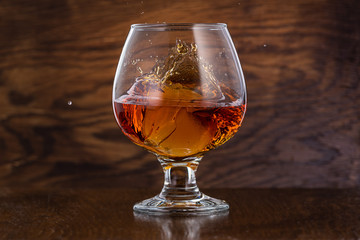 Splash in cognac glass from falling ice