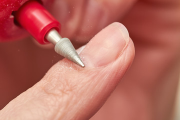 Woman filings nails with electric nail file at home. Electric Nail File Manicure Pedicure Drill. Manicure at home. Closeup, selective focus